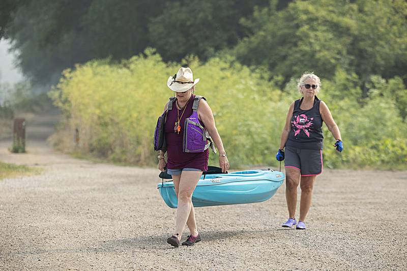 Cindy Muller (left) and Susan Gray lug carry a kayak to the launch pad on the Hennepin Canal at the Route 40 bridge Wednesday, June 28, 2023.