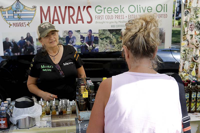 Marva Papadatos talks to a customer a on Tuesday, Aug. 27, 2024, at the Mavra’s Greek Olive Oil booth during the Summer Woodstock Farmers Market around the Historic Woodstock Square. People were able to shop from over 40 of their favorite farms & producers for in-season food fresh produce, dairy, meats, breads, baked goods, spices, herbs, pasta, flowers and more.