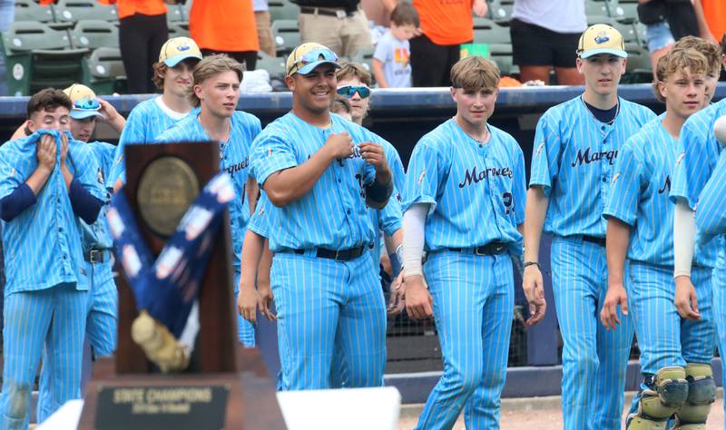 Members of the Marquette baseball team eye their Class 1A State championship trophy on Saturday, June 1, 2024 at Dozer Park in Peoria.