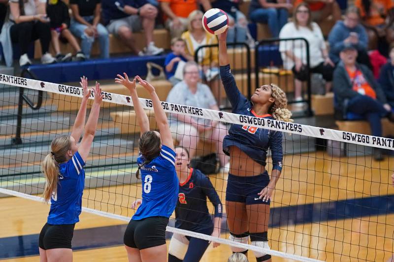 Oswego’s Maya Norlin (18) goes up for a kill attempt against Rosary’s Aerin Leonard (9) and Sarah Nierman (8) during a volleyball match at Oswego High School on Tuesday, Sep 3, 2024.