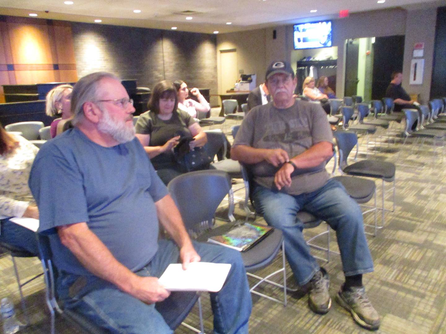 Former prison guards Mike Johnson (left) and Ron Trujillo await the start of.a meeting of the Joliet City Council, where they asked the city to get involved in lifting a ban that prevents them from visiting the Old Joliet Prison, where they were among 13 staffers and volunteers terminated a year ago. July 2, 2024