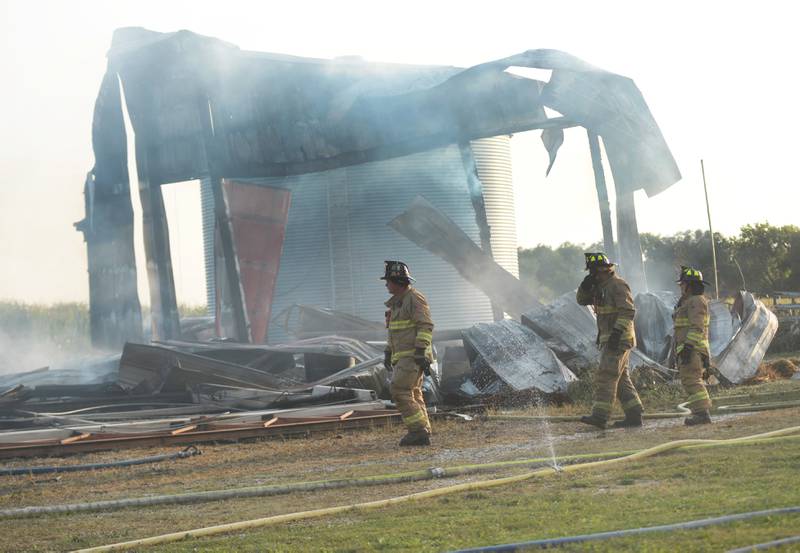 Firefighters walk past the remains of a large machine shed after it was destroyed by a fire on Monday evening Sept. 10, 2024. Several fire departments assisted the Polo Fire Department on the call at 7015 W. Judson Road, southeast of Polo.. There were no injuries.