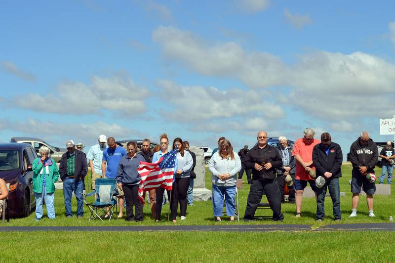 Residents of Polo stand and bow their heads in prayer during the invocation said at the city's Memorial Day ceremony in Fairmount Cemetery on Monday, May 27, 2024.