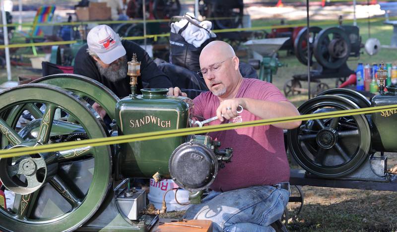 Frank DeVries of Plano repairs a 1926 Sandwich Co. hit and miss gas engine, while Bud Forrer of Shabbona works on another during the Sandwich Fair on Saturday, Sept. 9, 2023.