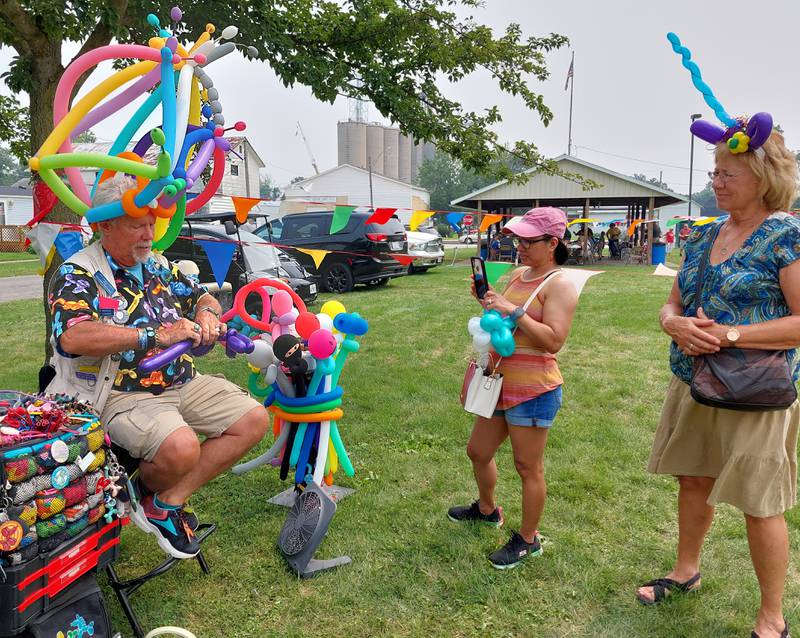 Balloon artist Doug Smith, of the Unique Twist, makes a balloon creation for Excel Harris, of Flanagan, and Patty Long, of Streator, on Sunday, July 16, 2023, during Long Point's Sesquicentennial celebration.