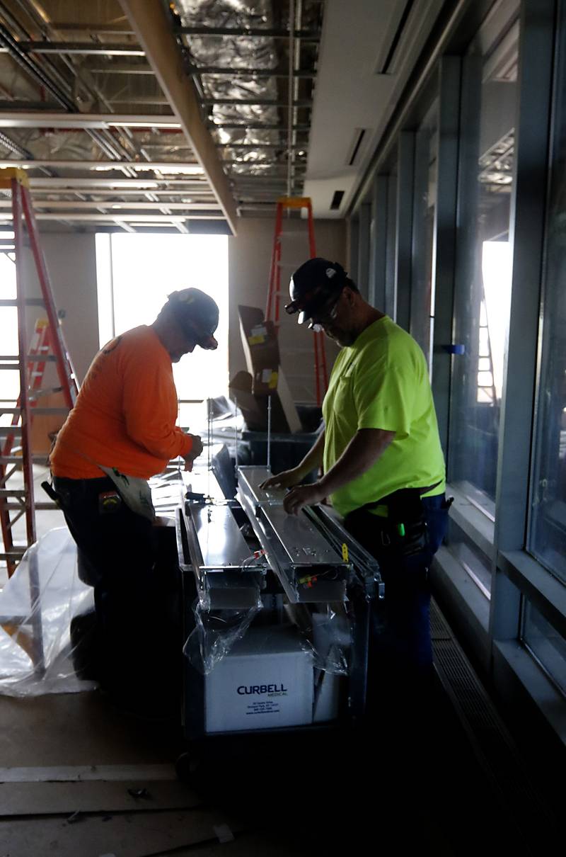 A construction worker installs lights in the cafeteria on Friday, April 21, 2023, as construction continues on the new Mercyhealth hospital in Crystal Lake. The hospital is ramping up hiring as it gets set to open in this summer.