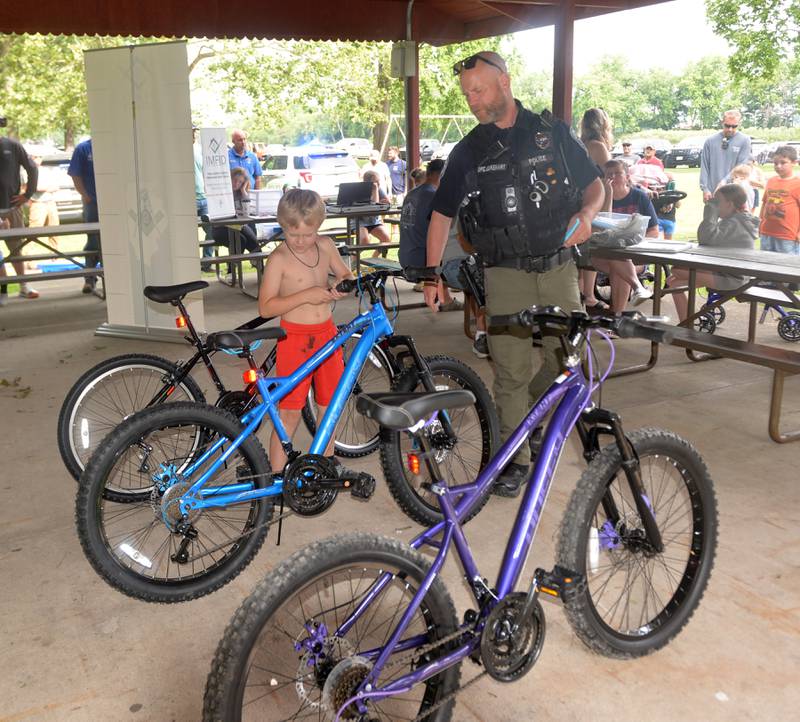 Reed Hill, 7, of Prophetstown, picks out a new bike with the help of Prophetstown Police Officer Will Lakehart at the 18th annual Dick Brown Fishing Derby at Prophetstown State Park on Saturday, June 15, 2024.