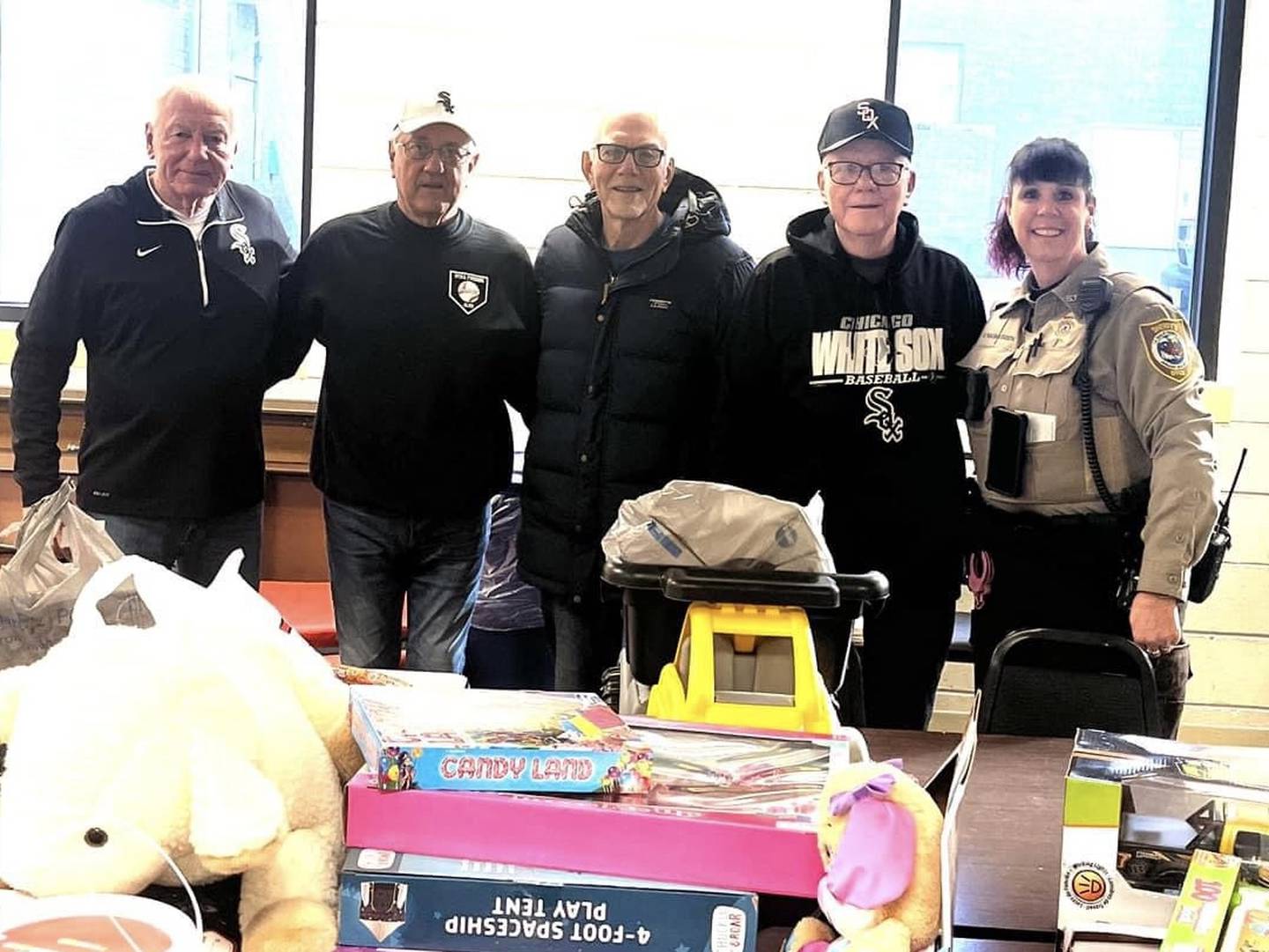 Members of the Utica Fireside White Sox Club pose with a La Salle County Sheriff's Deputy after donating to a holiday toy drive.