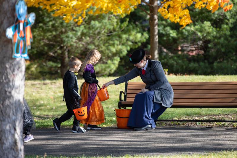 Katie Trchka of Darien, right, hands out candy to Boo Bash attendees at the Glen Ellyn Park District on Saturday, Oct. 22, 2022.