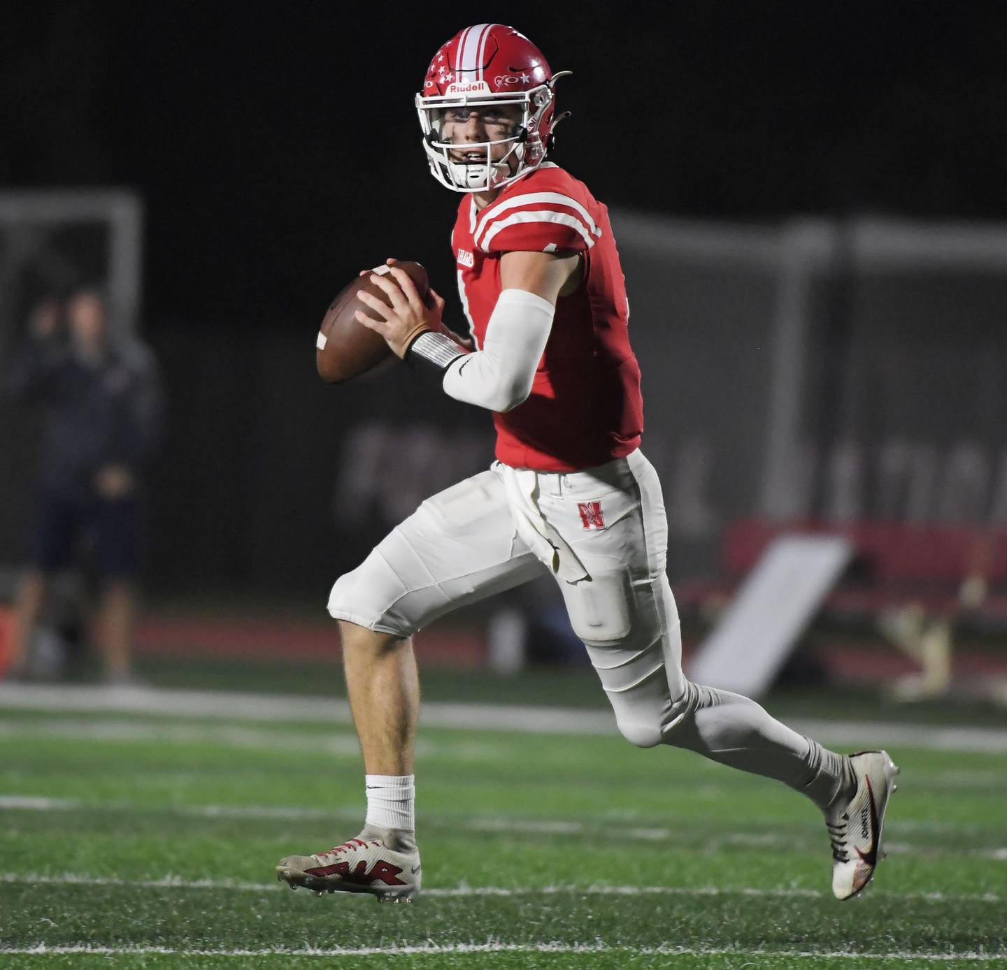 Naperville Central’s Jack Burton rolls out against Naperville North in a high school football game at North Central College in Naperville on Friday, September 29, 2023.