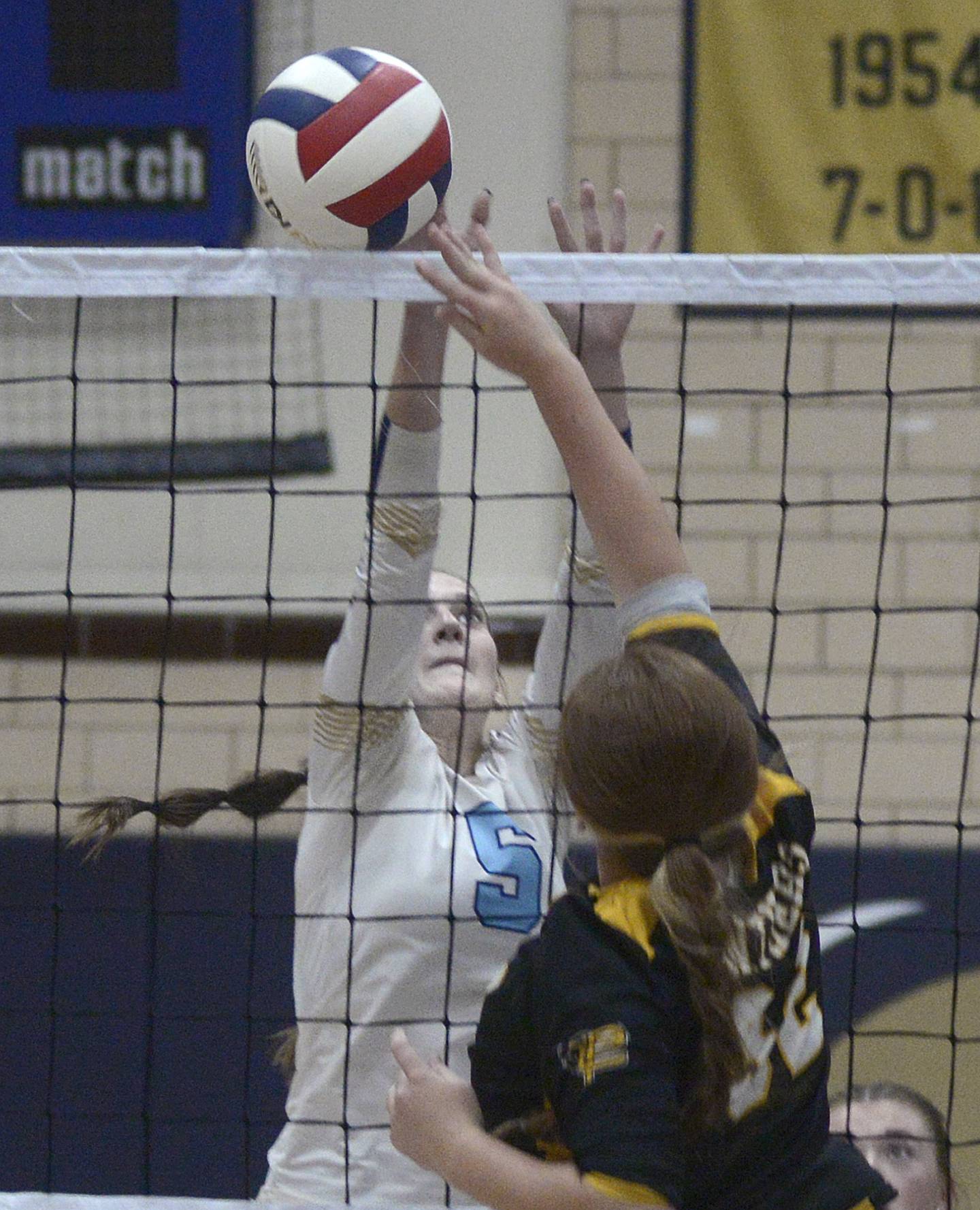 Putnam County’s Maggie Spratt pushes the ball past the block of Marquette’s Kealey Rick in the first set Thursday at Bader Gym in Ottawa.