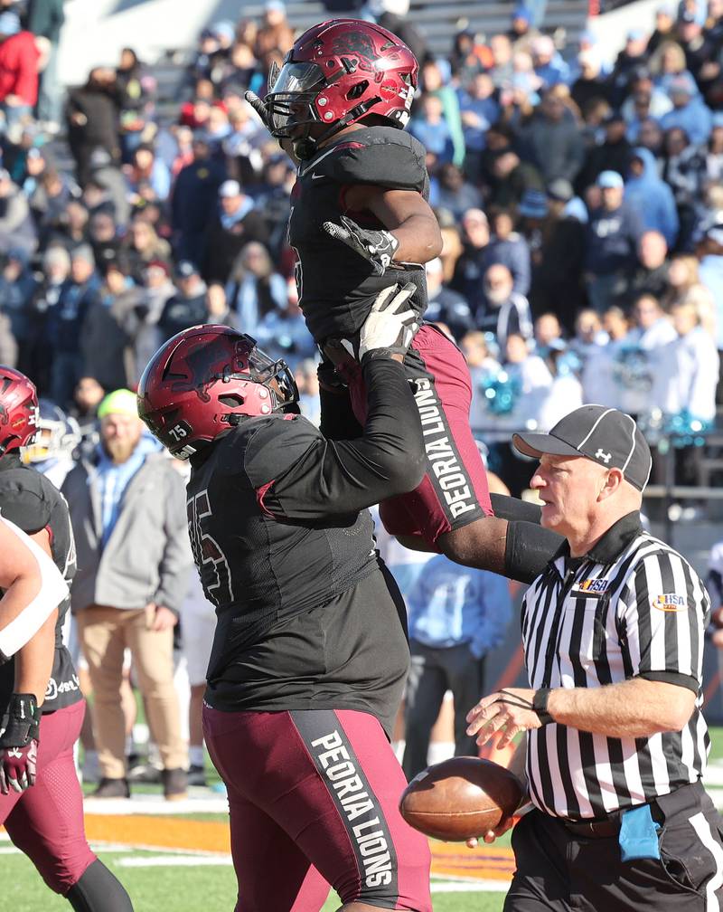 Peoria's Malachi Washington gets a lift from Peoria's Jaquarius Green after scoring a touchdown against Nazareth during their IHSA Class 5A state championship game Saturday, Nov. 26, 2022, in Memorial Stadium at the University of Illinois in Champaign.