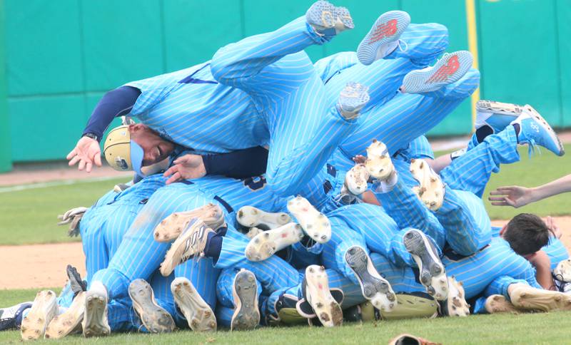 Marquette assistant coach Brad Waldron leaps on top of a pile of his players after defeating Altamont to win the Class 1A State championship title on Saturday, June 1, 2024 at Dozer Park in Peoria.