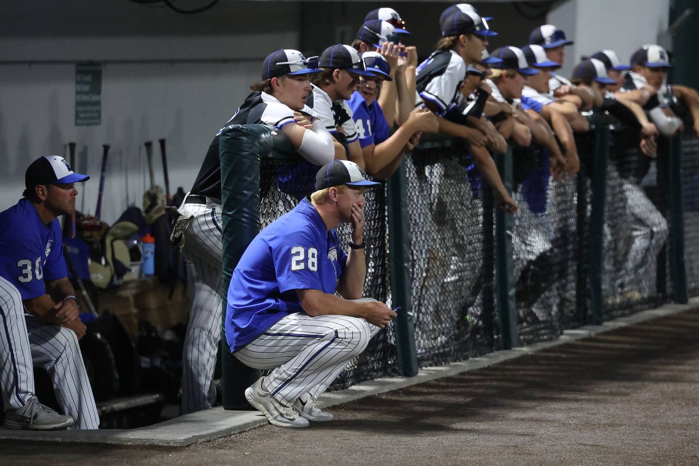 Lincoln-Way East head coach Eric Brauer kneels outside the dugout during the game against Brother Rice in the Class 4A Crestwood Supersectional on Monday, June 5, 2023 in Crestwood.