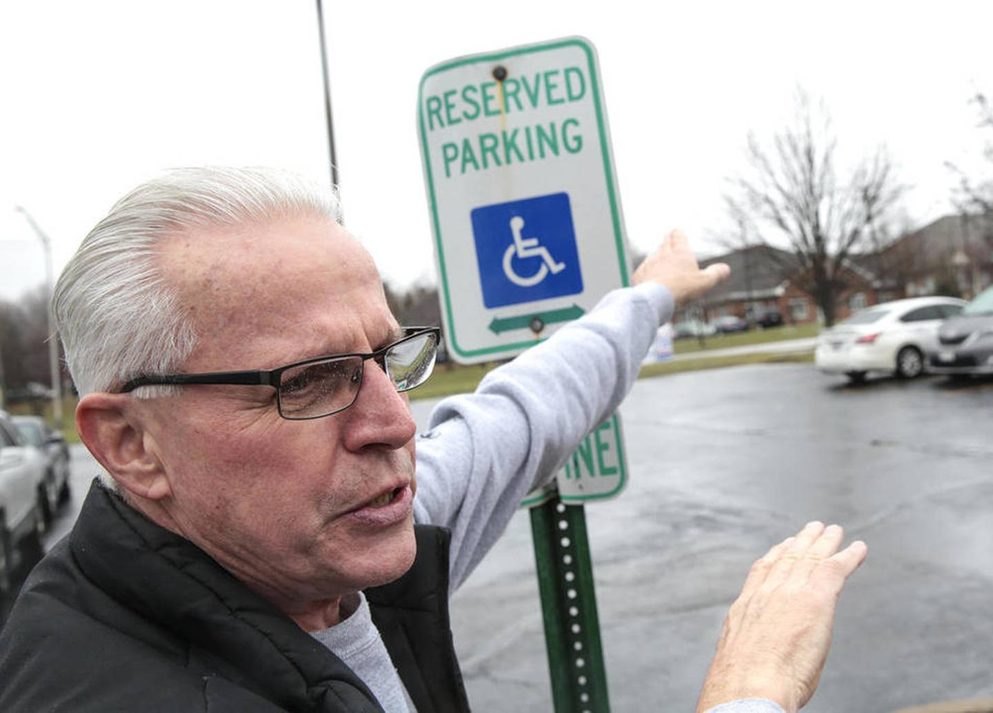 Disabilities advocate John Sheridan elaborates on how businesses can violate handicapped parking laws Wednesday along Essington Road in Joliet.