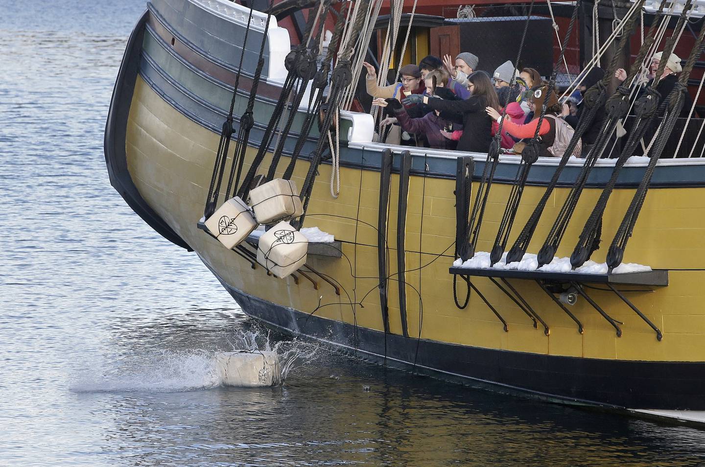 In this Dec. 11, 2017, photo, visitors to the Boston Tea Party Museum throw replicas of historic tea containers into Boston Harbor from aboard a replica of the vessel Beaver in Boston. On Dec. 16, 2023, the city marked the 250th anniversary of the revolutionary protest that preceded America’s independence.