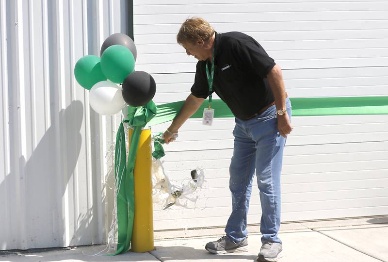 Oregonix Farms CEO David Schwimmer breaks a bottle on the side of the Oregonix Farms' new craft grow facility in Huntley on Friday, July 14, 2023. During the grand opening, guests were able to tour the facility.