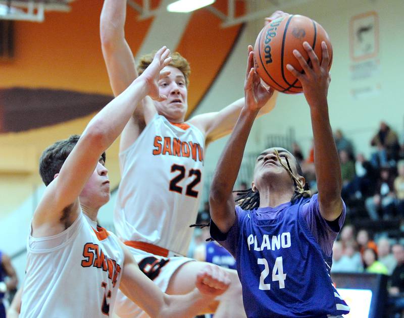 Plano's Ta'ron McGowan (24) atempts a shot against swarming Sandwich defenders Braden Behringer (12) and Dom Rome (22), during a varsity basketball game at Sandwich High School on Tuesday, Feb. 13, 2024.