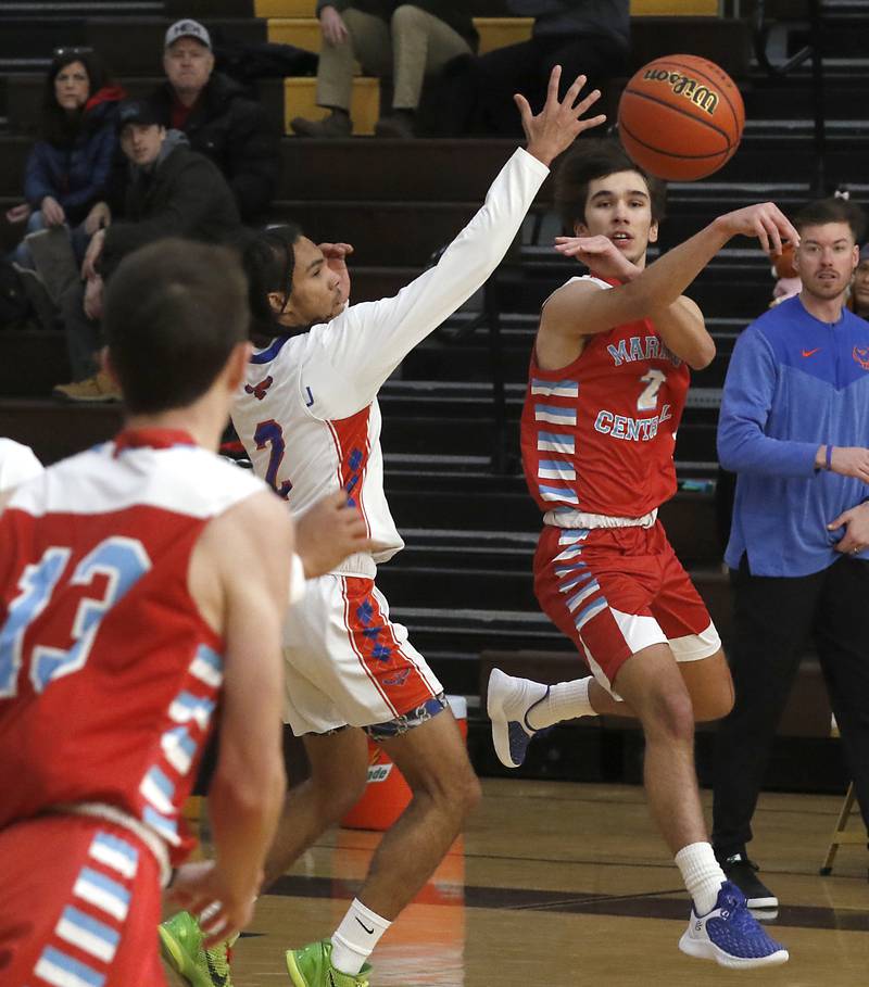 Marian Central's Jake Giangrego passes to a teammate, Michael Jablonski as he is defended by Hoffman Estates’ Jacob Atkins-Mirich during a Hinkle Holiday Classic basketball game Tuesday, Dec. 27, 2022, at Jacobs High School in Algonquin.