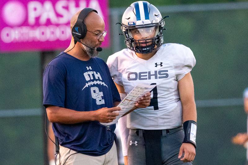 Oswego East's head coach Tyson LeBlanc gives instructions to Niko Villacci (4) during a football game against Waubonsie Valley in August 2023 at Waubonsie Valley High School in Aurora.