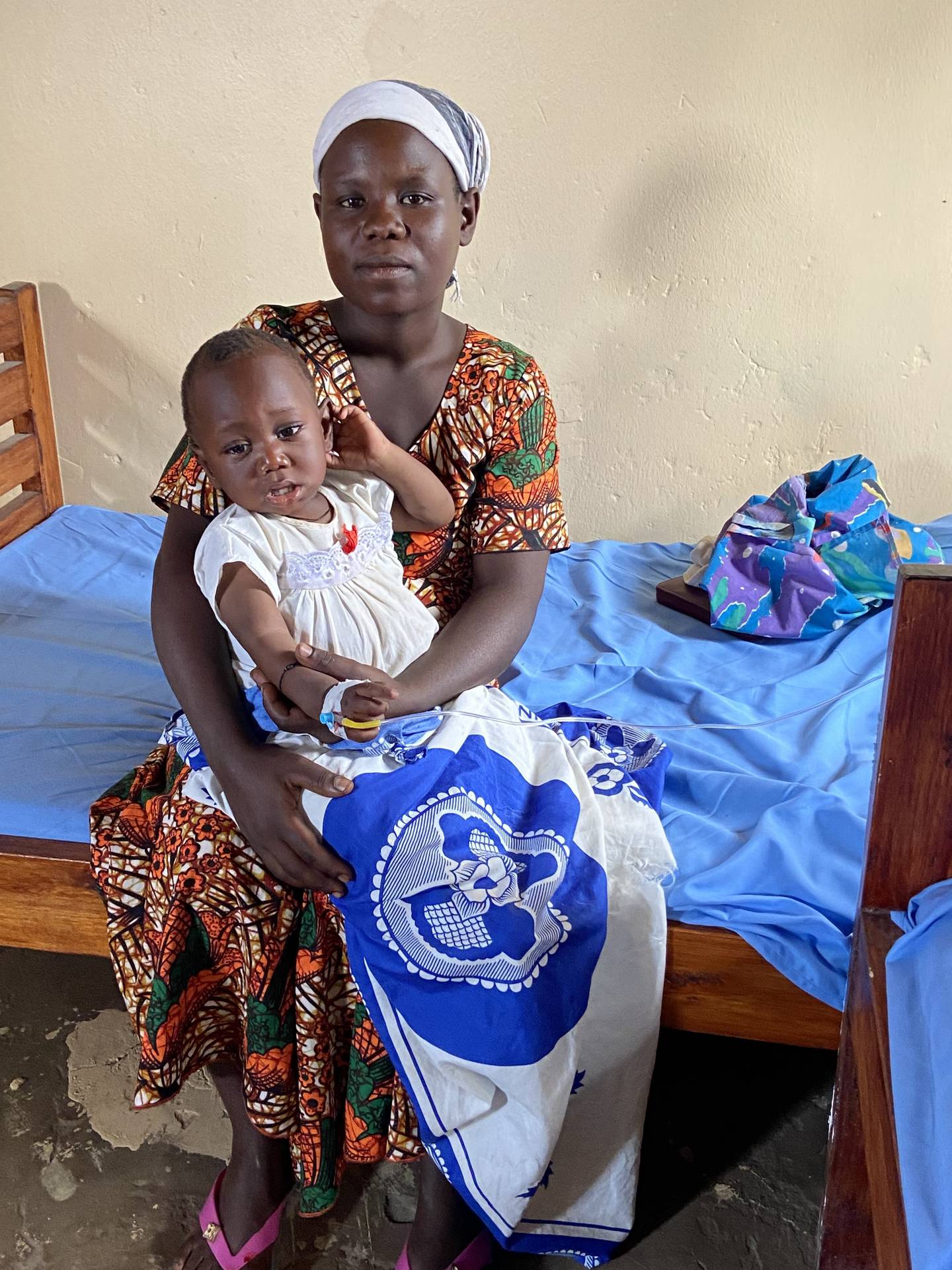 A mother rests while her daughter receives an IV.