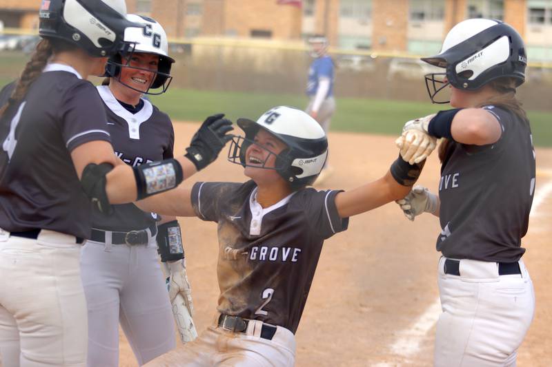 Cary-Grove’s Aubrey Lonergan is helped to her feet after collapsing in celebration following an inside-the-park home run against Burlington Central in varsity softball at Cary Monday.