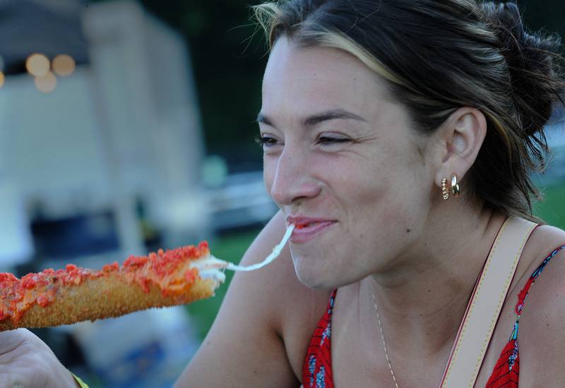 Emmy Anderson of Oswego does her best is the Korean Style Corn Dog she purchased from Lee's Concessions during the Oswegoland Park District's PrairieFest on Friday, June 14, 2024.