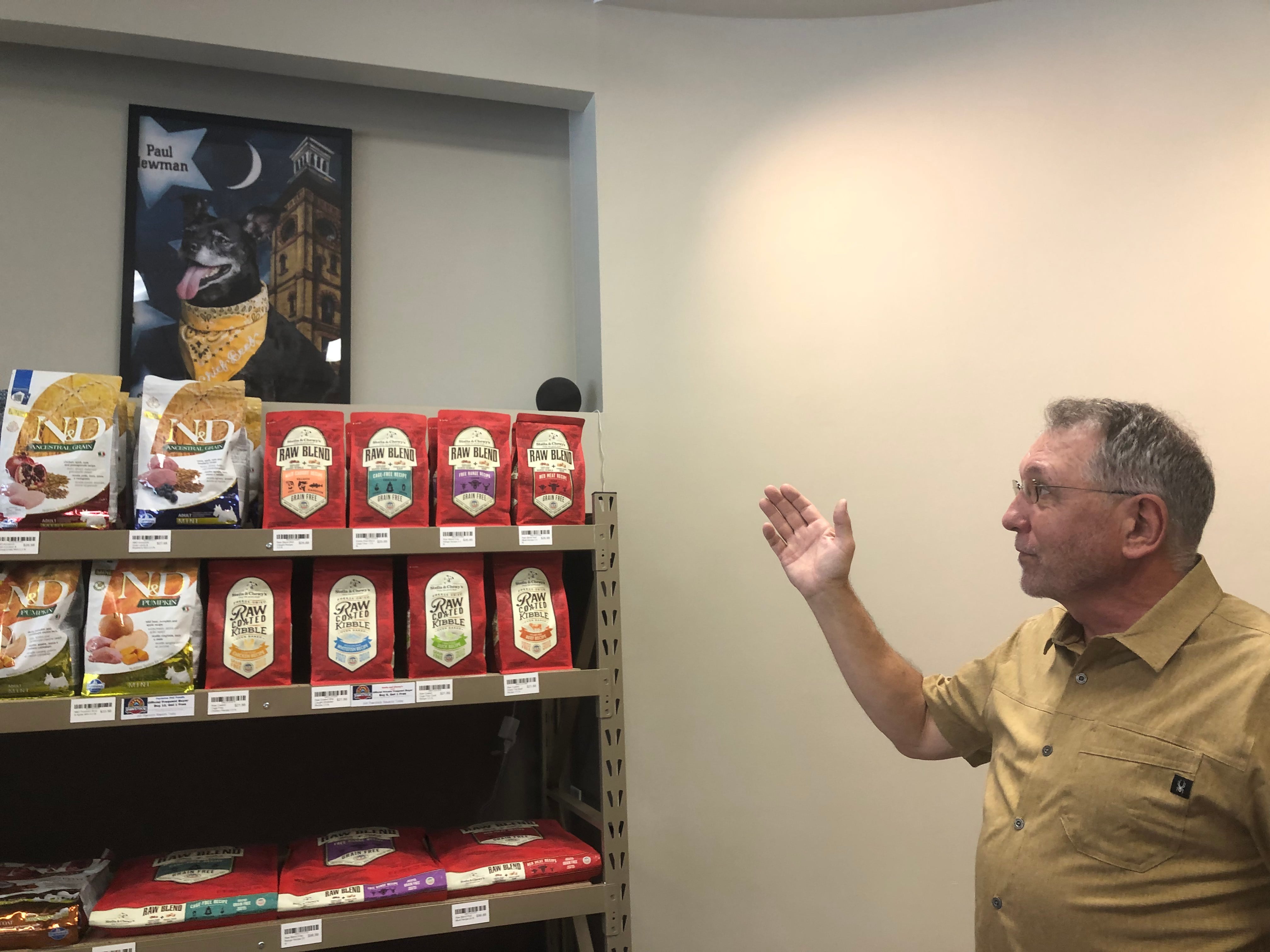 Pawstock owner Don Buss shows off the photo wall at the pet food store in Woodstock Aug. 1, 2024.