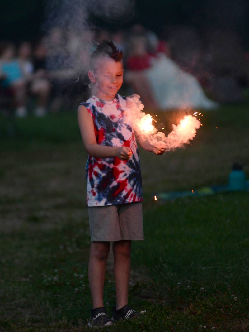 Theodore Davidson, 9. of Whitefish, Montana, plays with two sparklers as he waits for the fireworks to begin at Let Freedom Ring in Mt. Morris on Thursday, July 4, 2024.