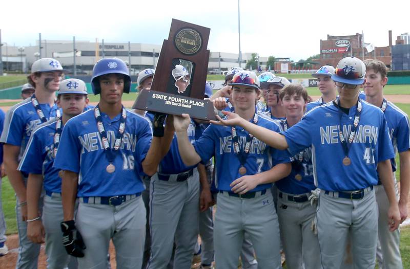 Members of the Newman baseball team hoist the Class 2A fourth place trophy on Saturday, June 1, 2024 at Dozer Park in Peoria.