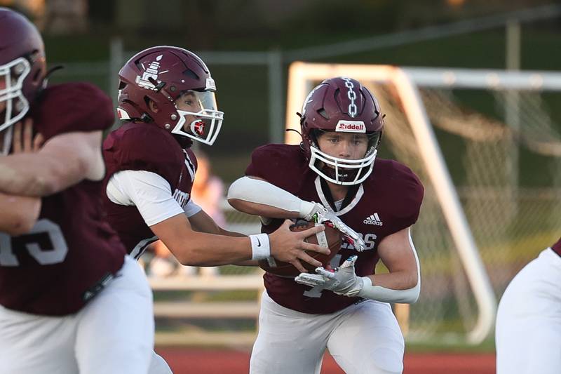 Lockport’s Brendan Mecher hands the ball off to Tyler Pospisil against Naperville Central on Oct. 4, 2024 in Lockport.