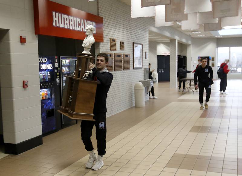 Vance Williams carries one of Marina Central’s trophies back to the trophy case after Marian Central honored their wrestlers that brought home the IHSA Class 1A Dual Team State Championship title on Friday, March 8, 2024, during a celebration at the high school in Woodstock.