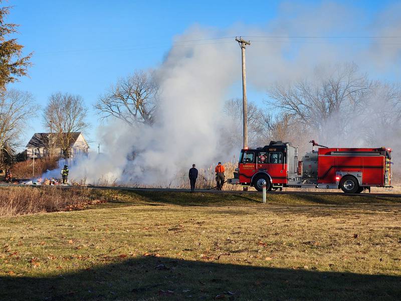 Firefighters work on knocking down the flames after a garbage truck's load of recycling caught on fire in the 7200 block of Huston Road near Braceville.