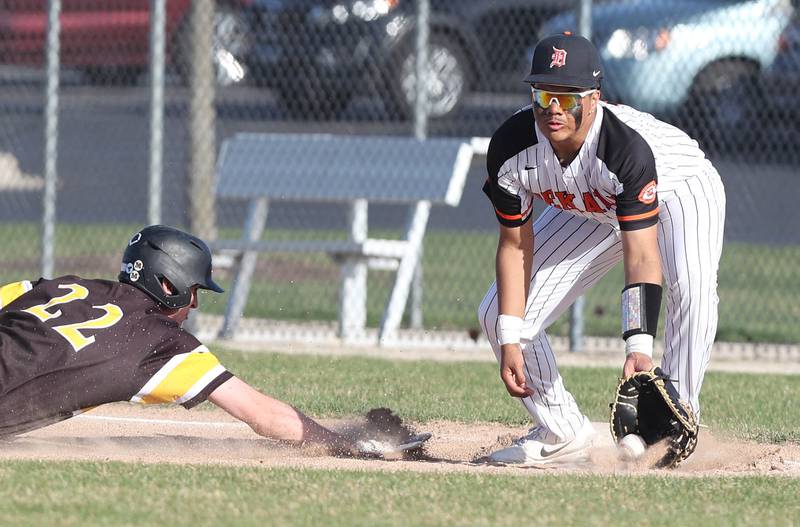 Metea Valley's Drew Hopkins dives back safely into first as DeKalb's Maddux Clarence picks the ball out of the dirt during their game Thursday, April 13, 2023, at DeKalb High School.