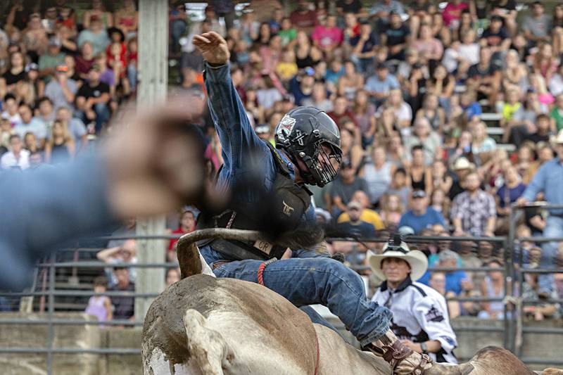 Brian Shuey hangs tough atop “Mr. No Name” in the Rice Bull Riding and Barrel Racing event Thursday, August 11, 2023 at the Carroll County fair.