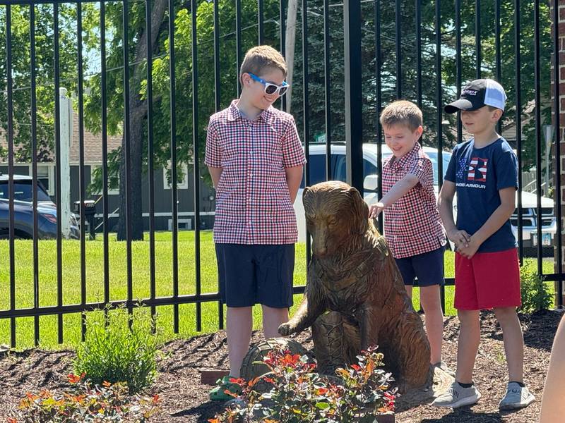 Kids unveil one of the statues at the new Veterans Dog Park in Minooka.