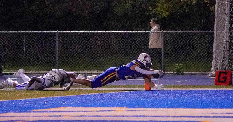 Wheaton North's Walker Owens (29) dives into the end zone for a touchdown against Geneva’s Dylan Reyes (5) during a football game at Wheaton North High School on Friday, Oct. 6, 2023.