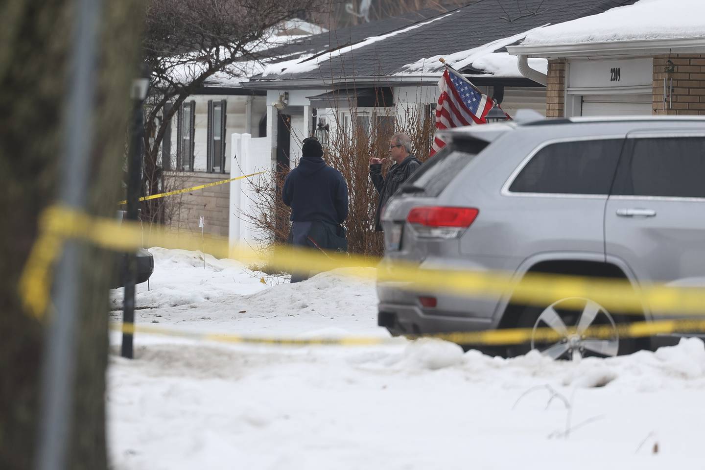 A resident who lives across from one of the homes where multiple victims were found shot dead along 2200 West Acres talks to a mail man on Tuesday, Jan. 23rd in Joliet.