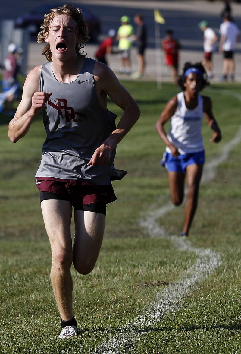 Prairie Ridge’s Will Gelon sprints to the finish line on front of Woodstock’s Ishan Patel during the boys race of the McHenry County Cross Country Meet Saturday, August 27, 2022, at Emricson Park in Woodstock.