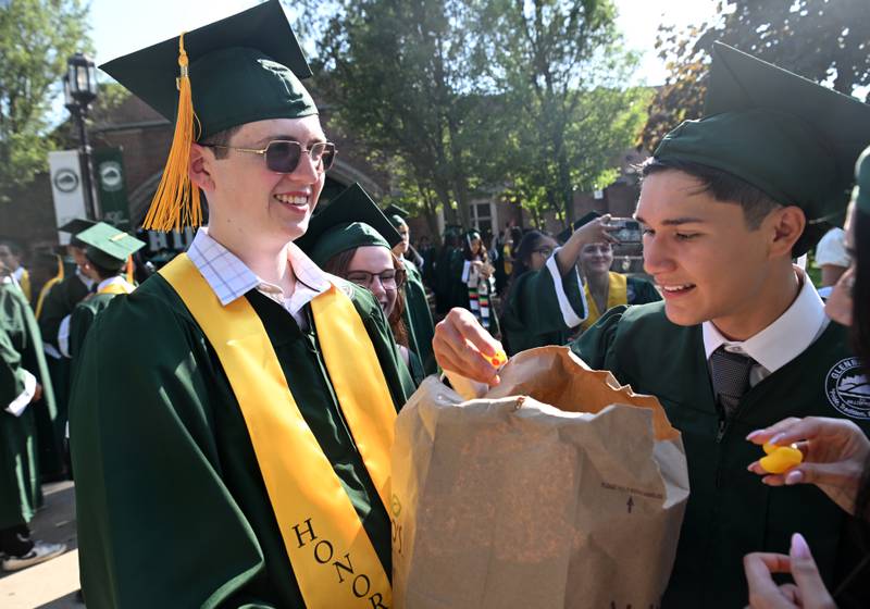 Jack Martin, left, passes out squeaky rubber ducks to graduates including Anthony Magadan prior to the start of the Glenbard West graduation ceremony on Thursday, May 23, 2024 in Glen Ellyn.