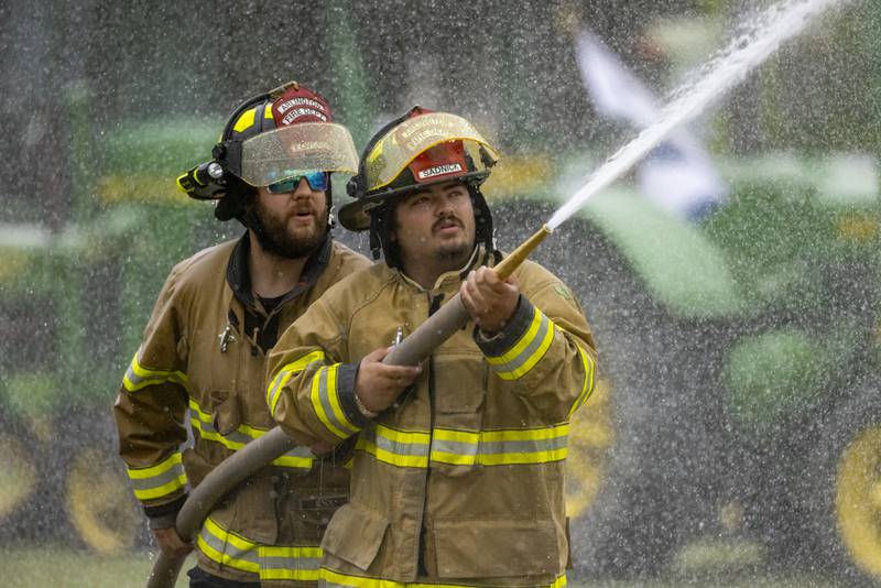 Chase Sadnick (front) and Anthony Lovgren push forward while competing in the fire hose tug of war event Saturday, June 8, 2024, at Buffalo Days in La Moille.