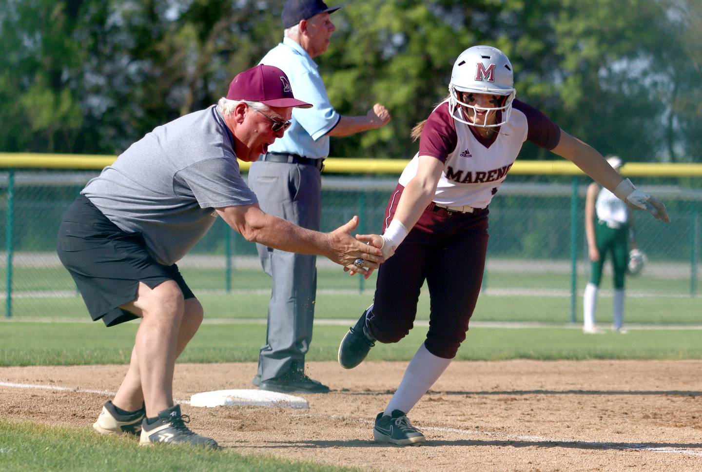 Marengo’s Gabby Christopher is greeted by third base coach Rob Jasinski on a Christopher home run against North Boone in IHSA Softball Class 2A Regional Championship action at Marengo Friday.