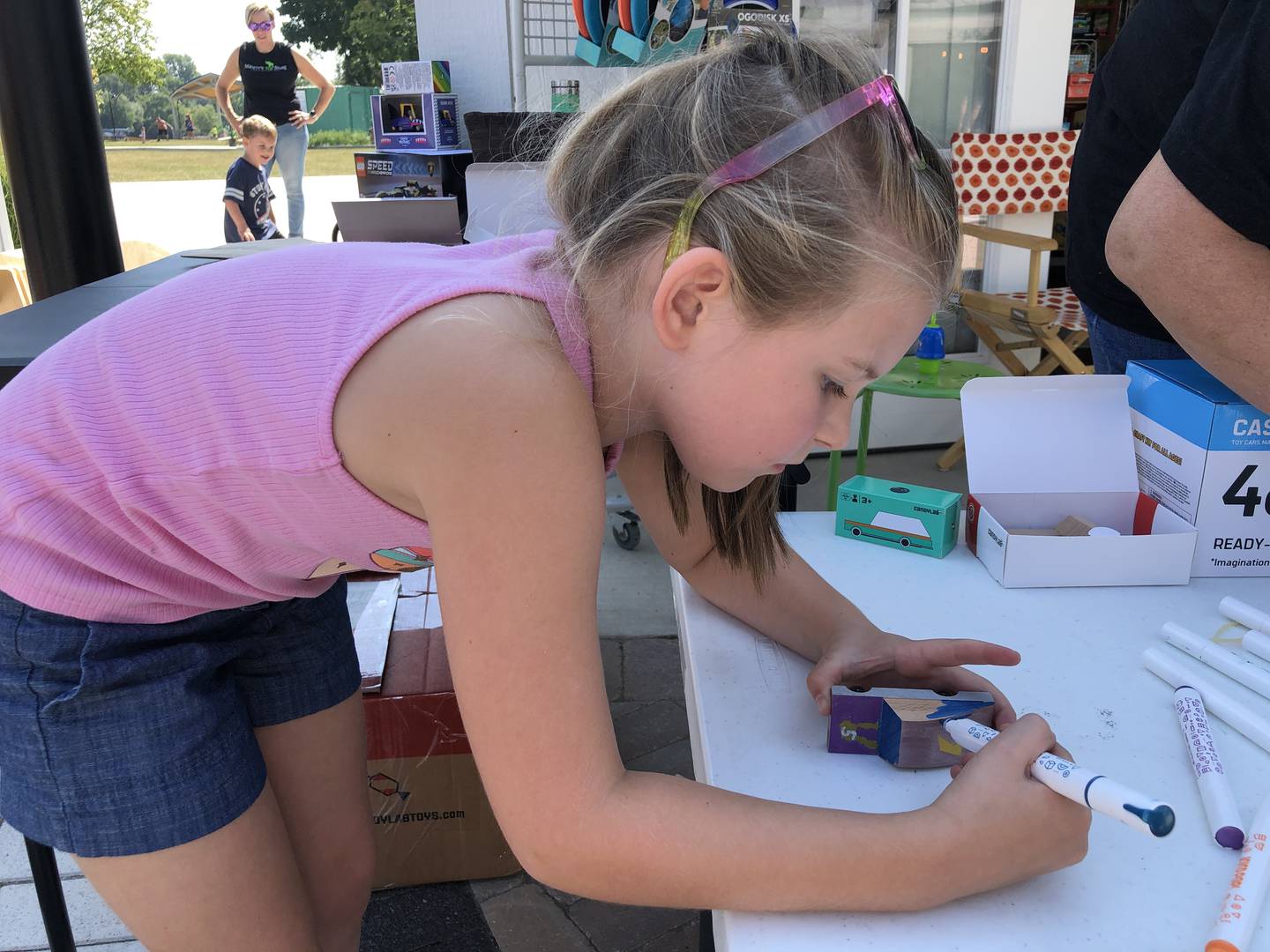 Ady Miller, 6, of McHenry, intently decorates her race car on Saturday, Aug. 24, 2024, outside Marvin's Toy Store at McHenry's Riverwalk Shoppes.