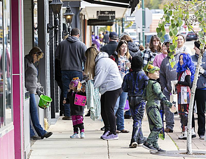 Posing as the mysterious catwoman, Barb Schmiedeb (left) hands out treats in front of Asterix boutique Saturday, Oct. 28, 2023. Several downtown businesses handed out candy as part of the Treat Street event.