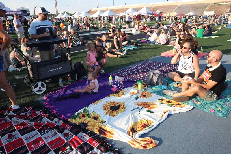 A group of friends find a spot on the field to relax and enjoy the music at the Taste of Joliet on Friday, June 21, 2024 at Joliet Memorial Stadium.