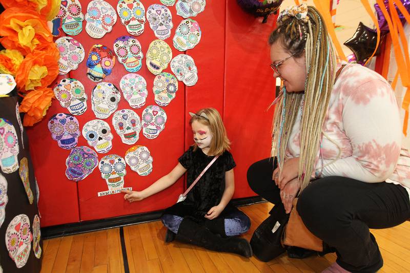 Olivia Schlangen, 7, of Spring Grove shows her mother, Vanessa, a skull craft she made to honor her grandpa, Lenny, featured during the Dia de los Muertos, Day of the Dead event at Stanton Middle School on November 4th in Fox Lake. The event was sponsored by the Bilingual Parents Advisory Committee (BPAC) from School Districts 114,124 and 37. Students were able to wear their Halloween costumes to the event.
Photo by Candace H. Johnson for Shaw Local News Network