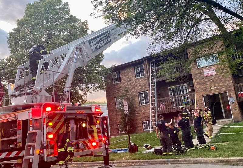 A DeKalb fire engine deploys a ladder truck as a firefighter scales upwards to reach the roof where the worst of the smoke swelled as crews responded to a structure fire at a Husky Ridge apartment complex in the 800 block of Kimberly Drive, DeKalb, on Wednesday evening, May 29, 2024.