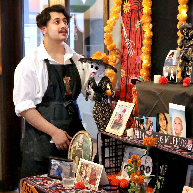Tomas Zuniga, a waiter at El Jimador Mexican Grill, checks out the community ofrenda Tuesday, Oct. 31, 2023, that is set up at the restaurant in DeKalb. DeKalb will be hosting a Day of the Dead "Celebration of Life" Saturday, Nov. 4.