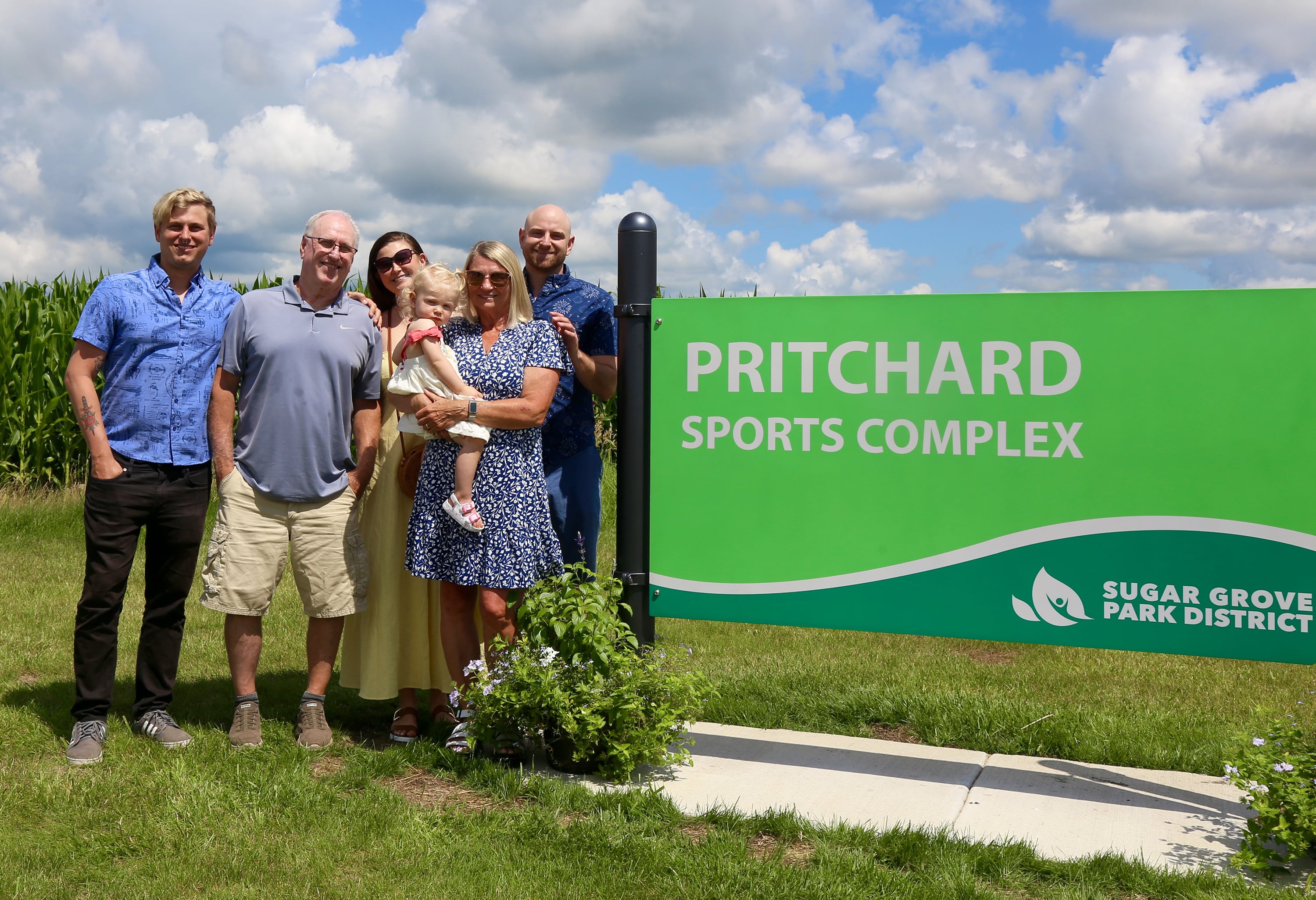 Karen Pritchard poses with her huband, twin sons, daughter in law and granddaughter next to the new sign erected in her honor on July 6, 2024 in Sugar Grove.