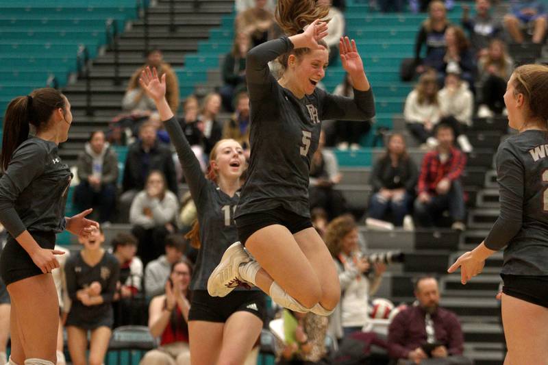 Prairie Ridge’s Grace Jansen, center, and the Wolves celebrate a point against Woodstock in IHSA Class 3A sectional semifinal volleyball action at Woodstock North Monday.